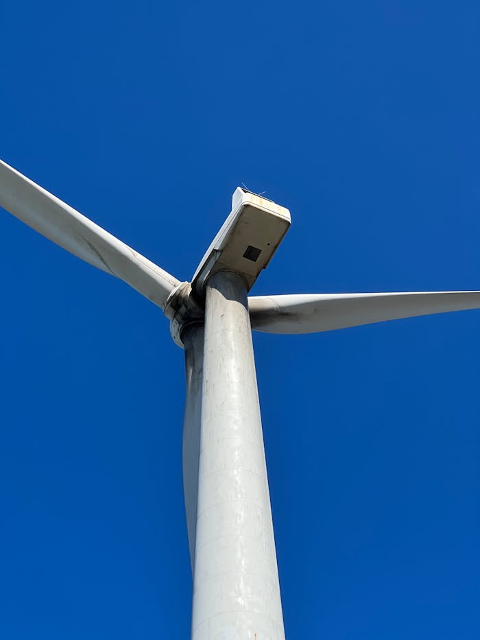Close-up view of a wind turbine with clear blue sky, showcasing renewable energy.